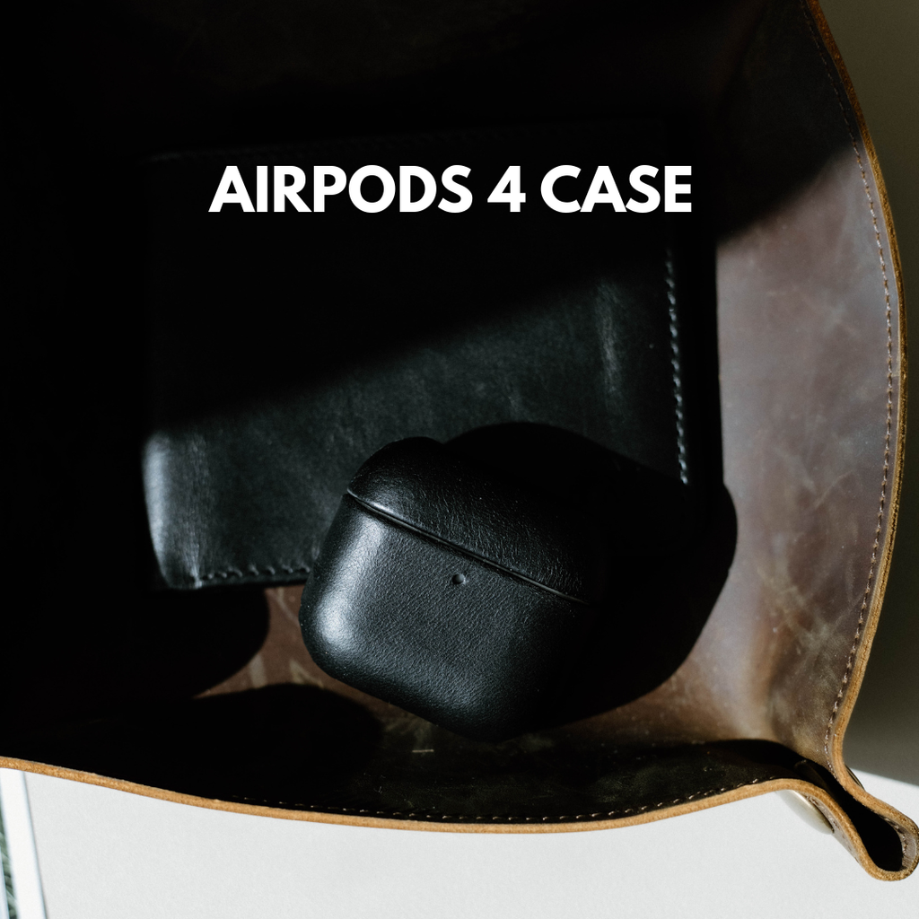 Close front view of black leather AirPods 4 case showing smooth grain and seam on a leather tray with wallet and headline AIRPODS 4 CASE
