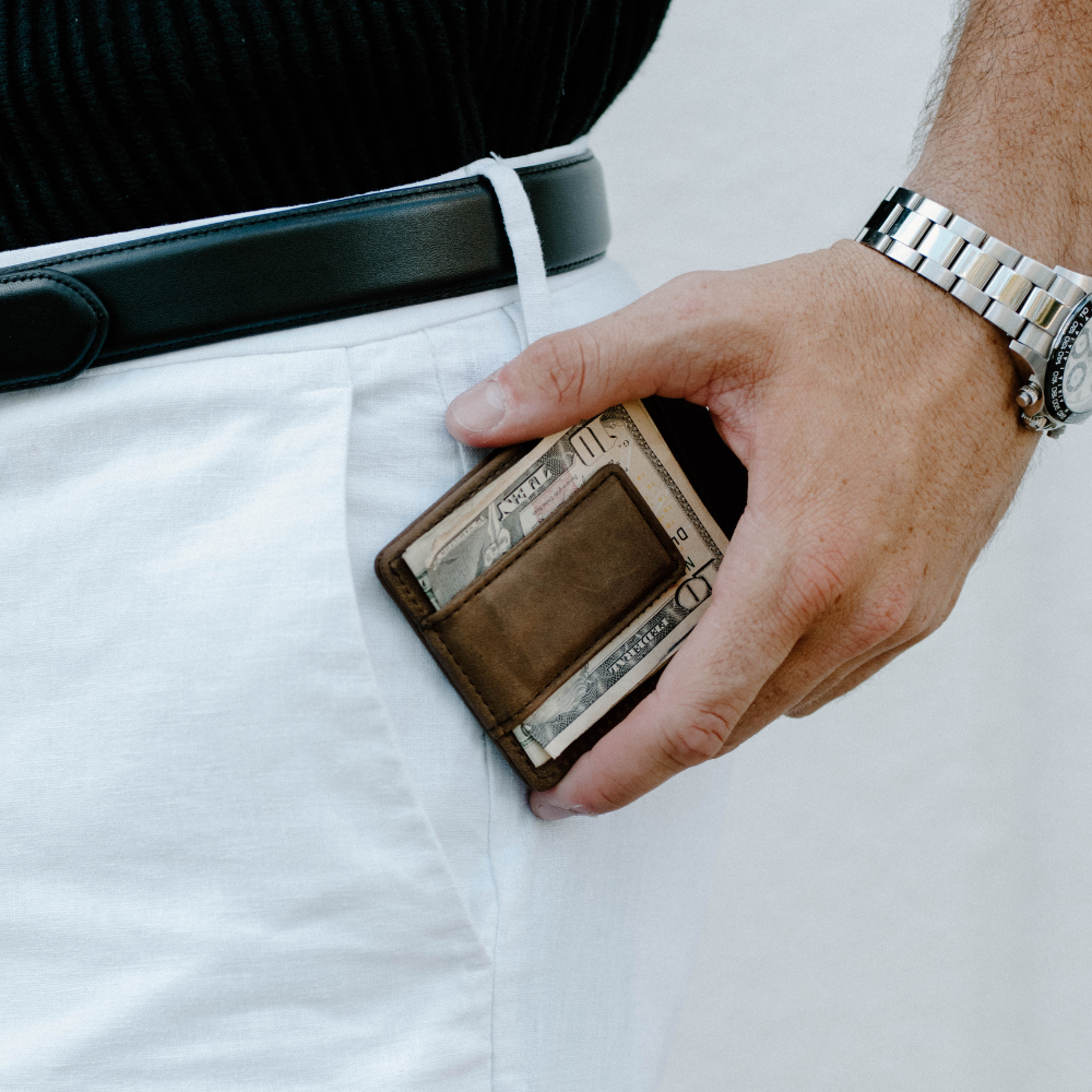 A person holding the Money Clip wallet with cash visible, showcasing its slim design.