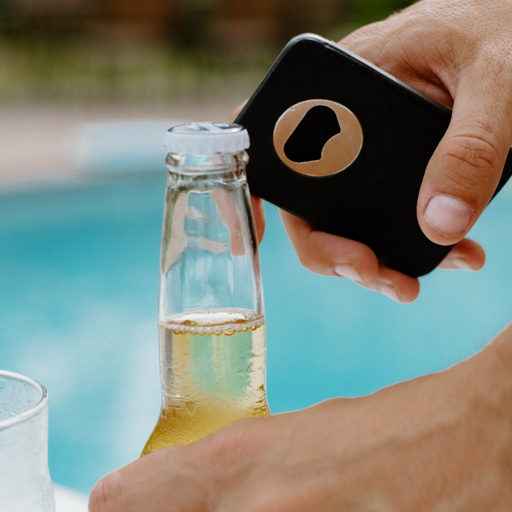 A person using a black magnetic wallet to open a bottle.