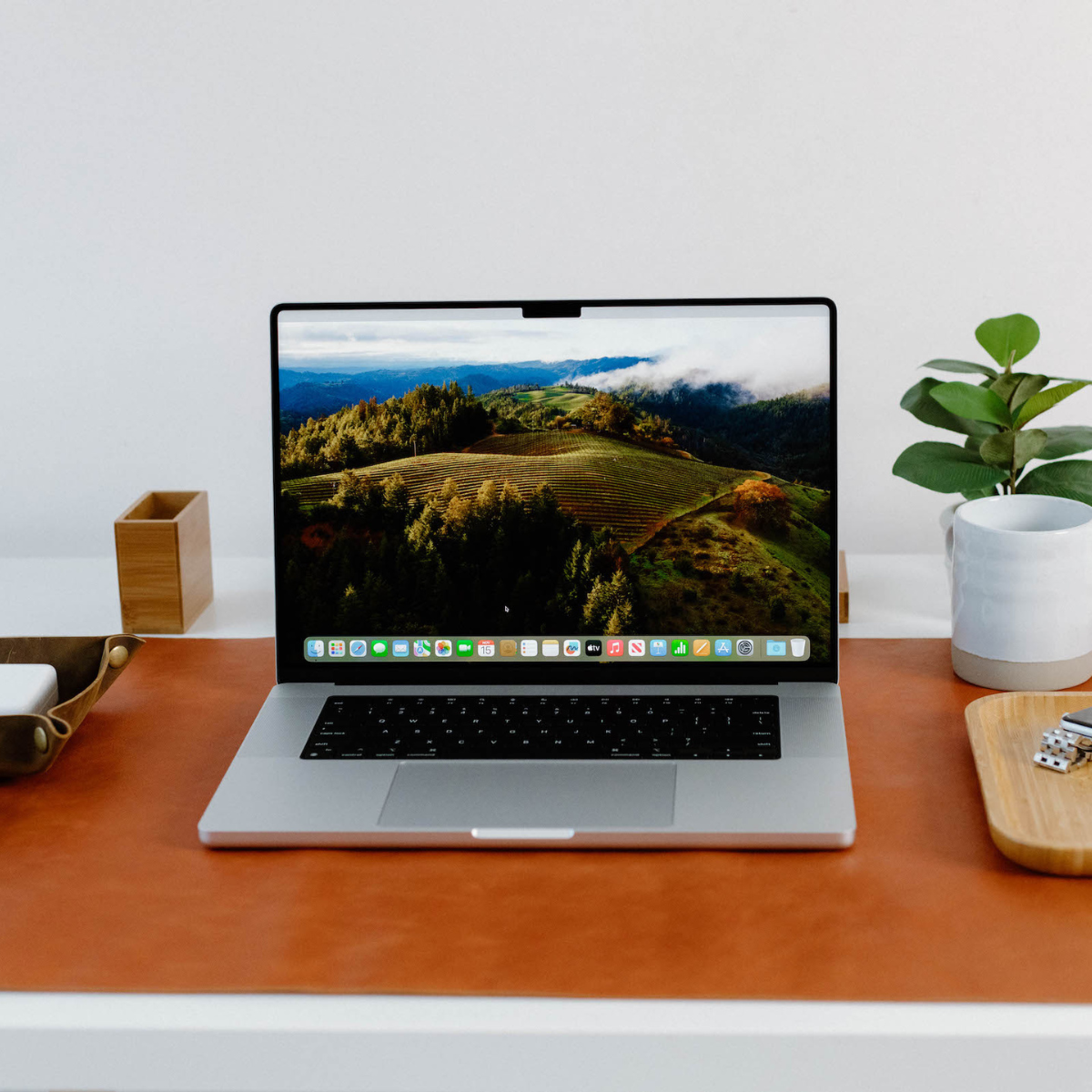 A laptop on a leather desk mat with a scenic background