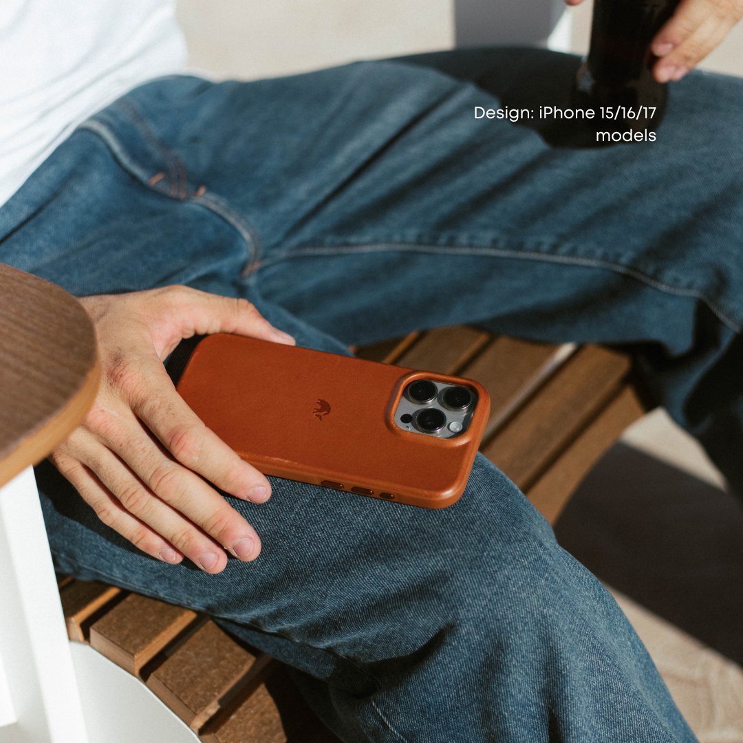 Brown sienna leather phone case resting on a person's denim-clad lap, phone camera lenses visible.