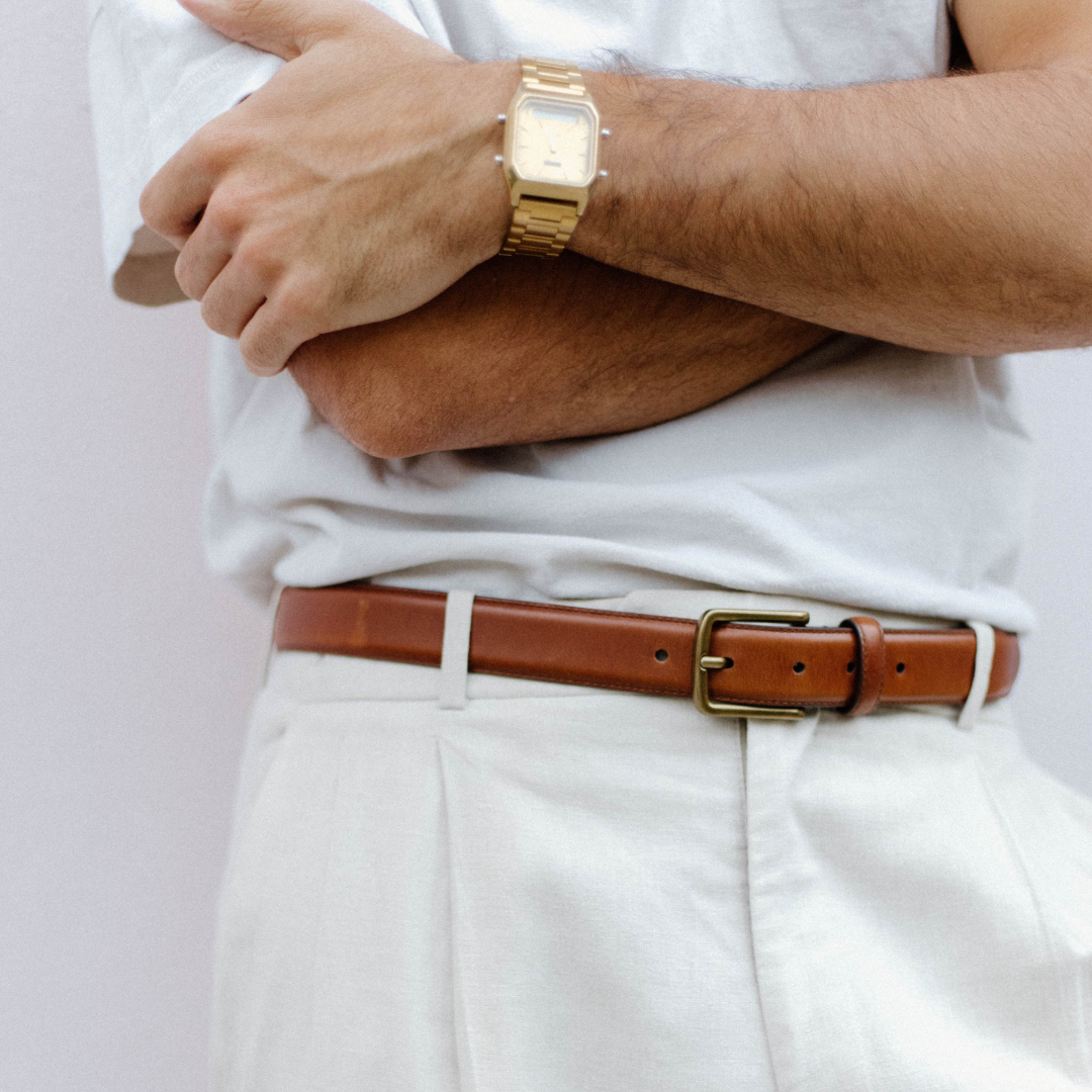 A person wearing a cognac leather belt with a gold watch, showcasing the belt's design.