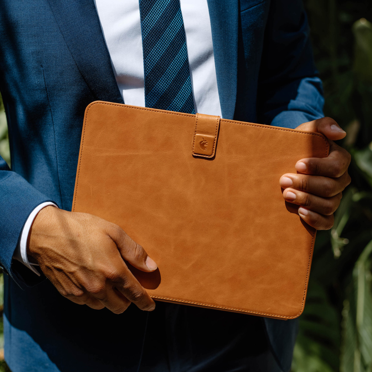 Person in a blue suit holding a tan leather iPad case