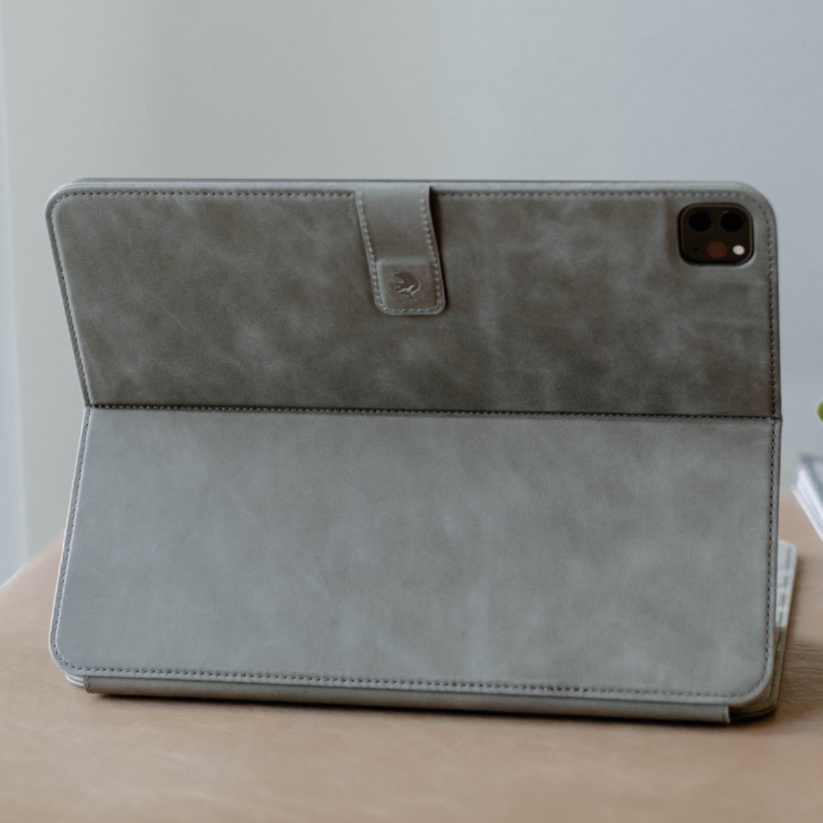 Back view of a gray leather iPad case with a clasp.