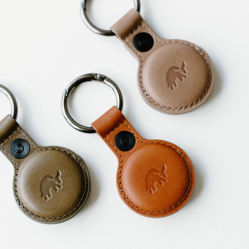 Three leather BullTags for AirTag in brown, tan, and sienna colors with embossed logo.
