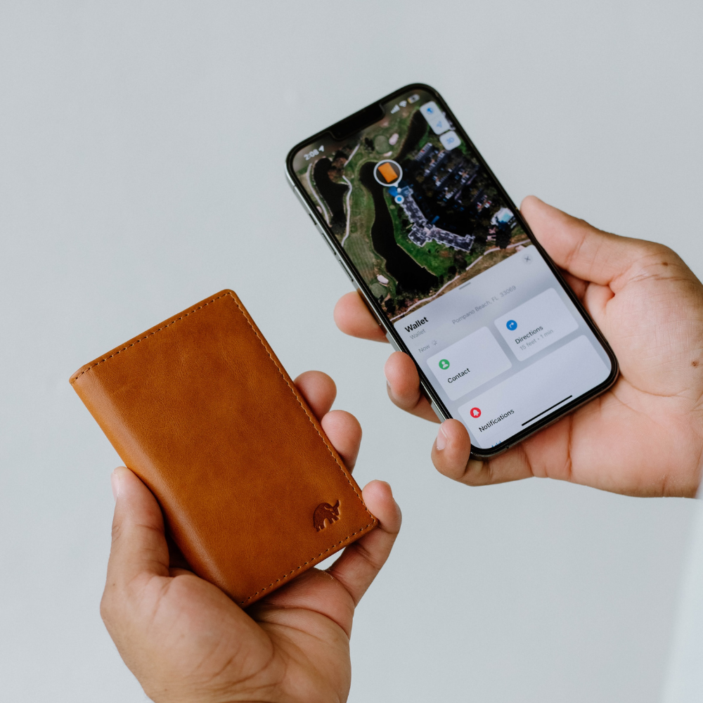 A person holding a brown leather wallet and a smartphone displaying a map.