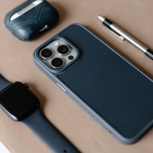 The FRWD Cases - SOLSTICE phone case in navy blue with camera cutout, placed on a flat surface with accessories.
