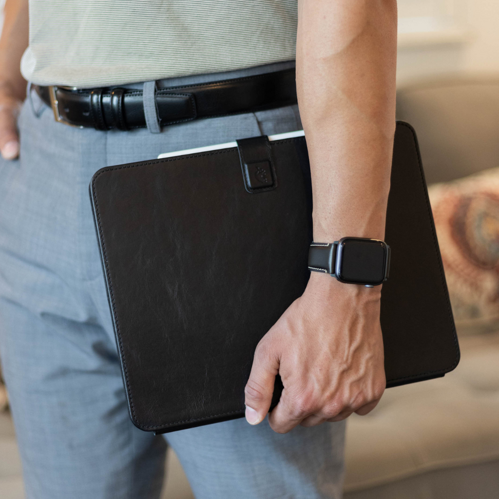 Man holding black leather iPad folio case at his side, Apple Watch visible on wrist