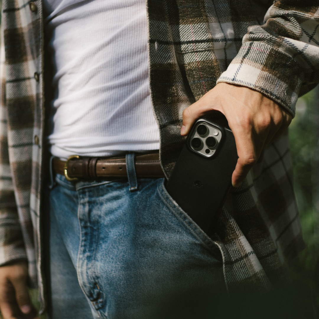 Hand sliding a black minimalist phone case into a front jeans pocket