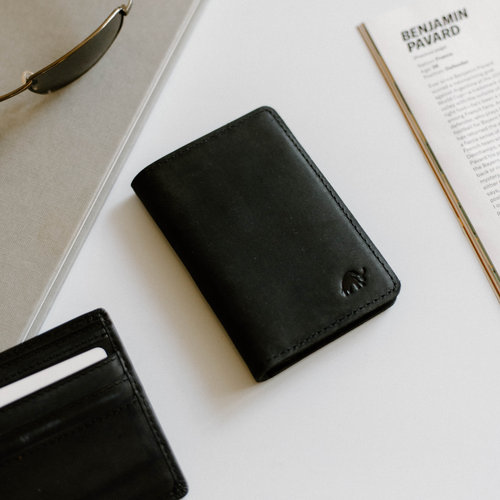 Black leather messenger wallet with embossed elephant logo, beside magazine titled BENJAMIN PAVARD