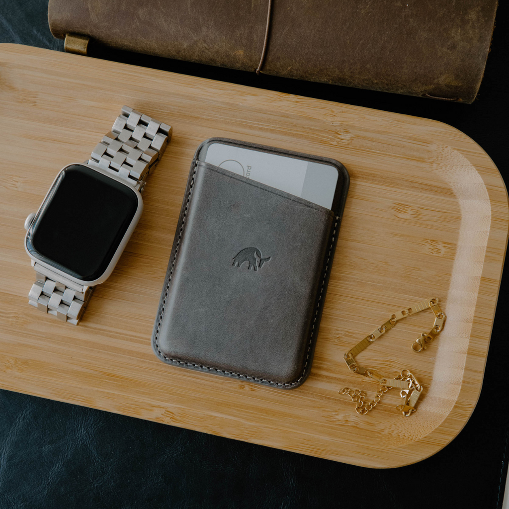 Leather Magnetic Wallet in Slate color, displayed with accessories on a wooden tray.