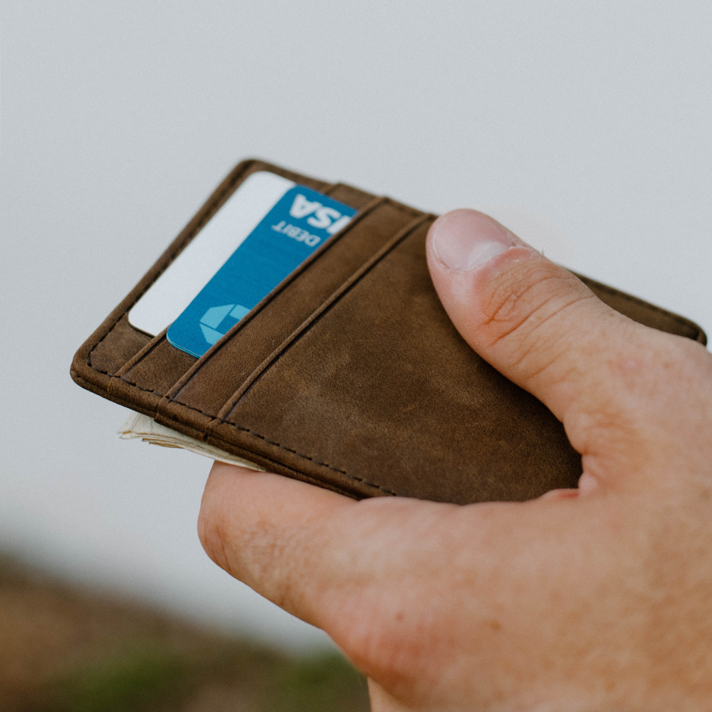 A hand holding the Money Clip wallet with cards and cash visible.