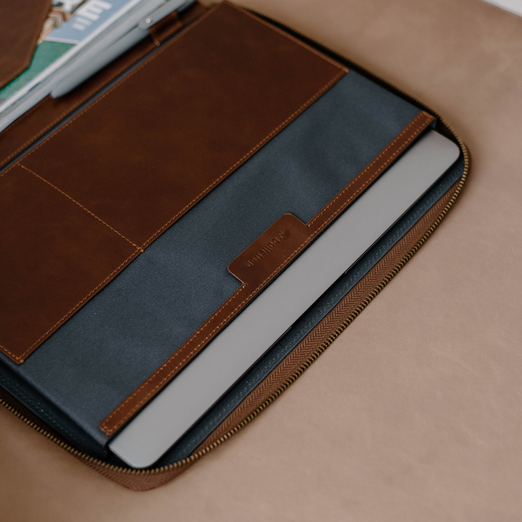 Interior view of the Leather MacBook Sleeve showing compartments and a MacBook inside.