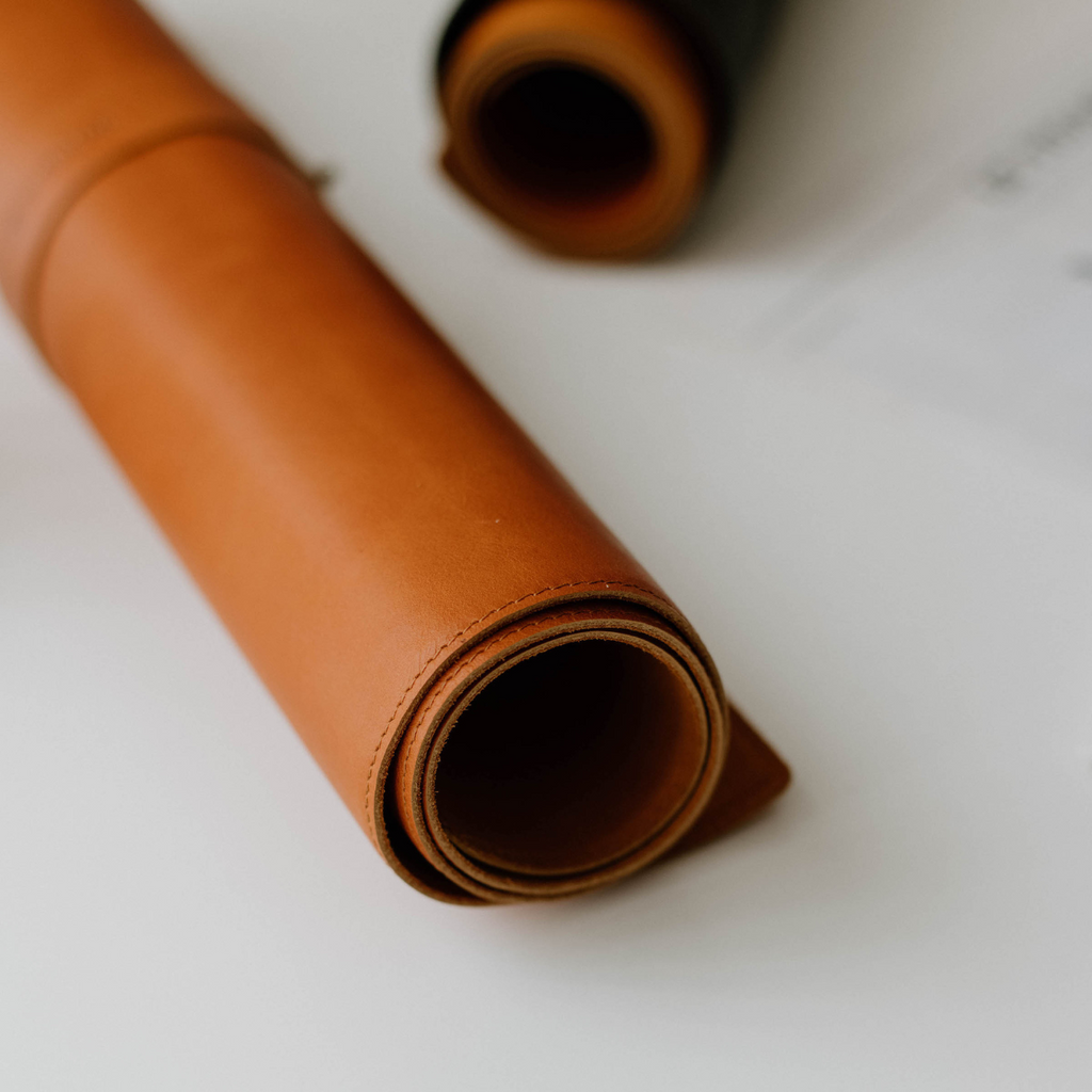 Rolled leather desk mat in sienna color, showcasing its texture and quality.