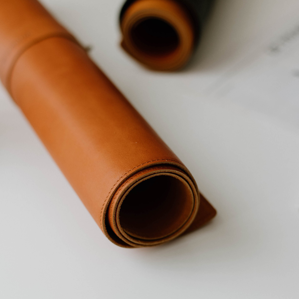 Rolled leather desk mat in sienna color, showcasing its texture and quality.