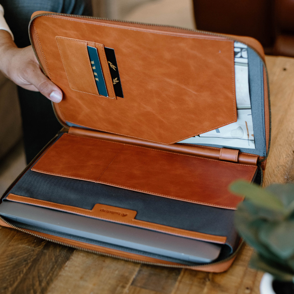 Sienna leather sleeve unzipped to show padded laptop compartment, two card slots with cards, and gray interior lining
