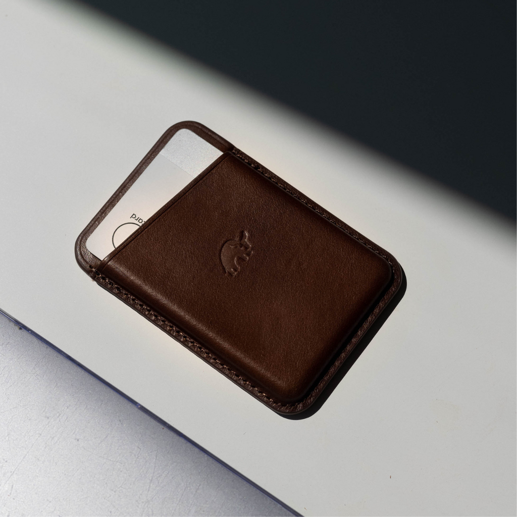 Brown leather magnetic card wallet with embossed elephant logo and a card partially inserted.