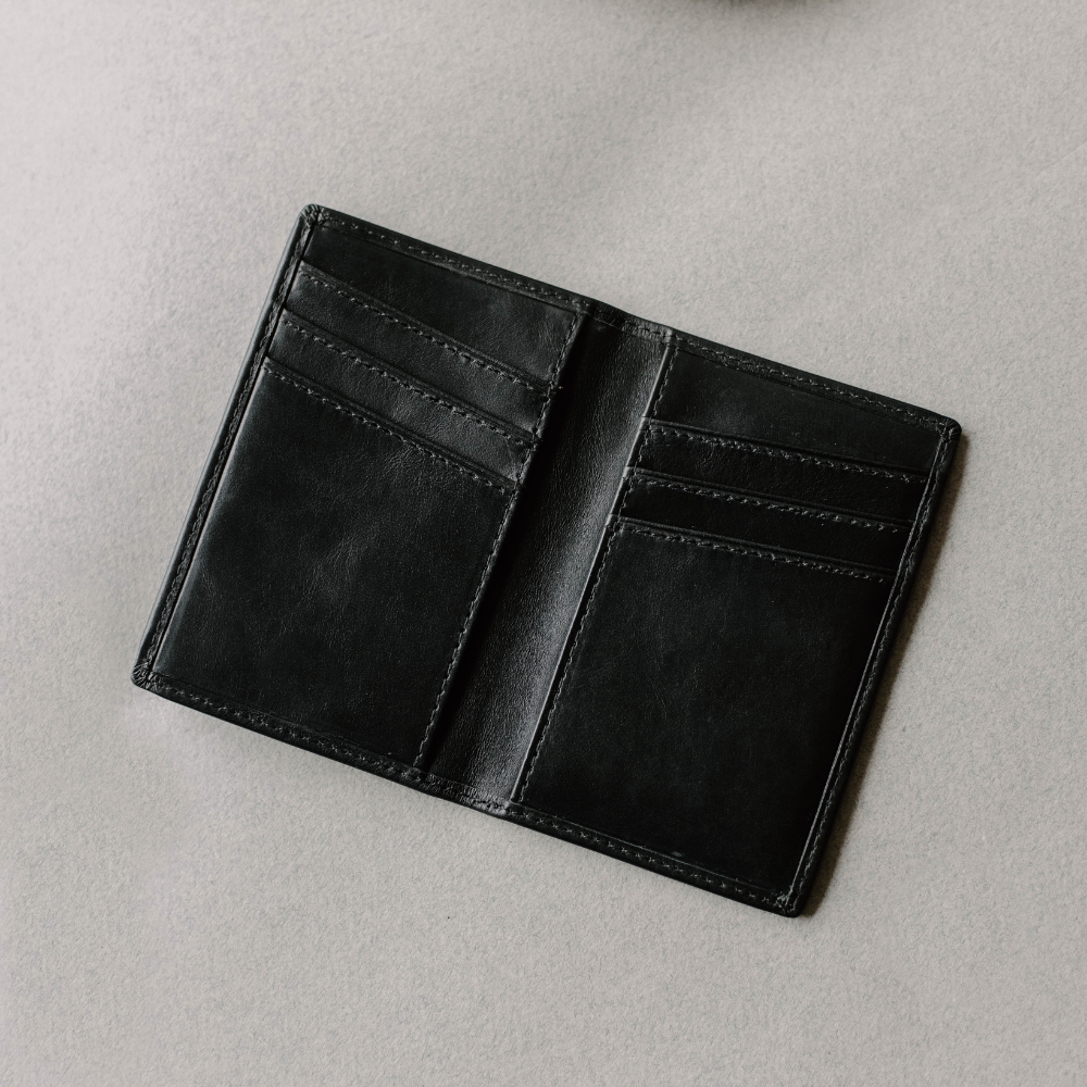 Black leather bifold wallet open showing three card slots on each side and two inner pockets
