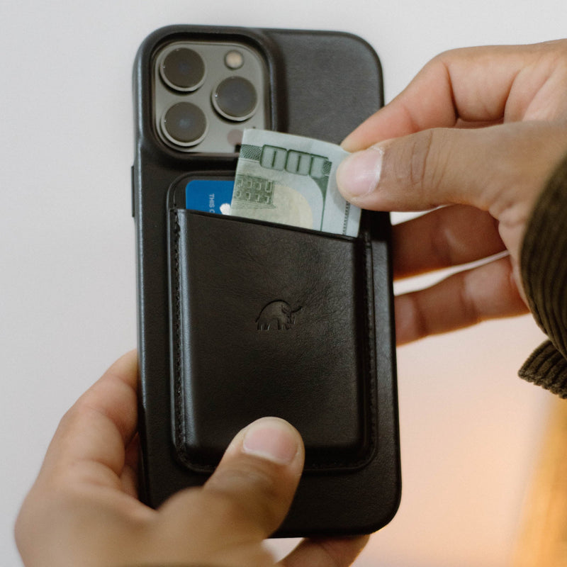 Black leather card wallet attached to phone case, blue card and folded 100 bill being pulled out by two hands