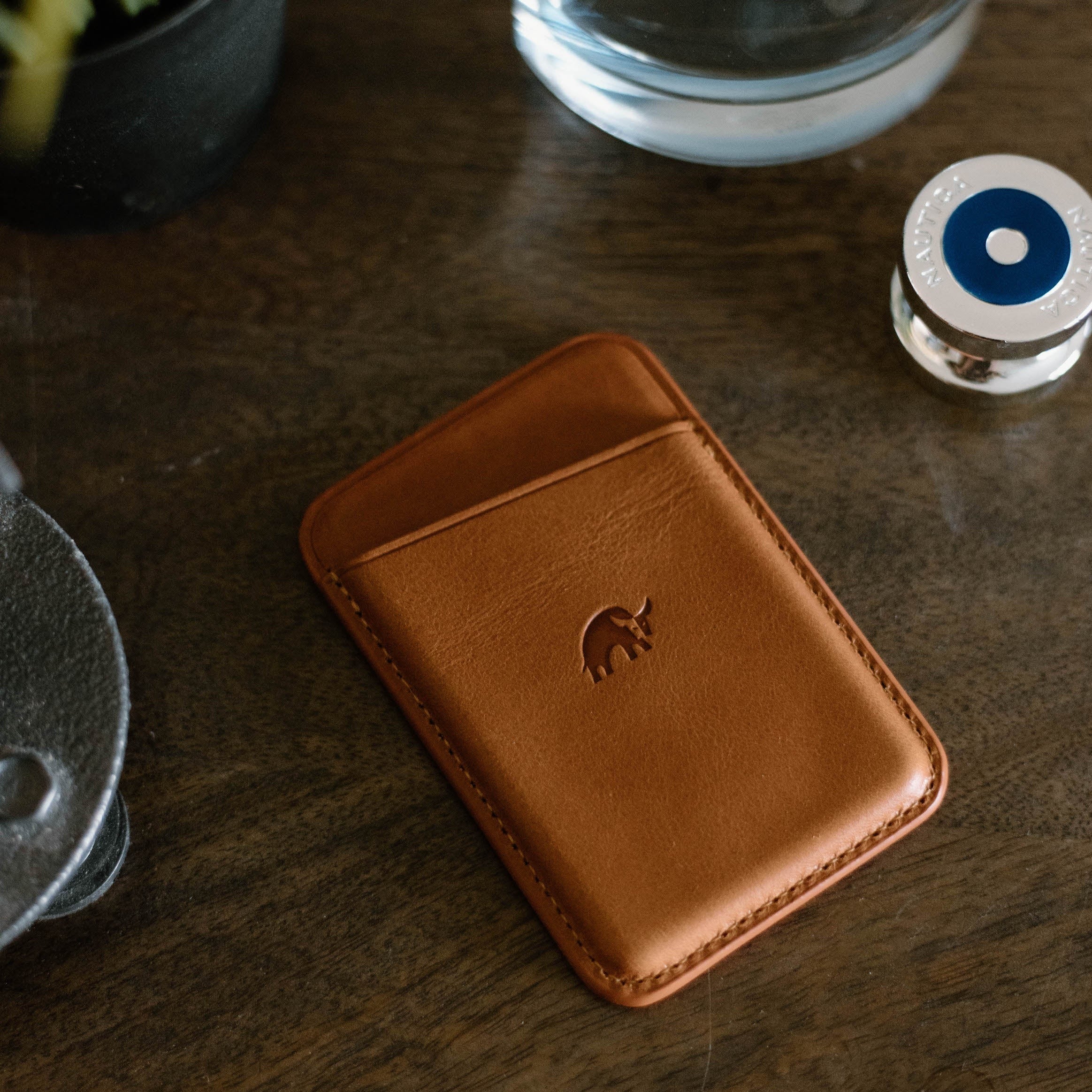 Leather Magnetic Wallet in Sienna color on a wooden surface with a logo embossed.