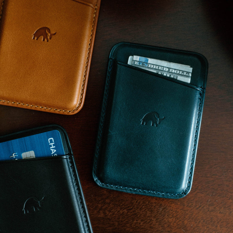 Top-down view of Leather Magnetic Wallet in Ocean showcasing folded cash in rear pocket and embossed rhino logo on wooden tabletop