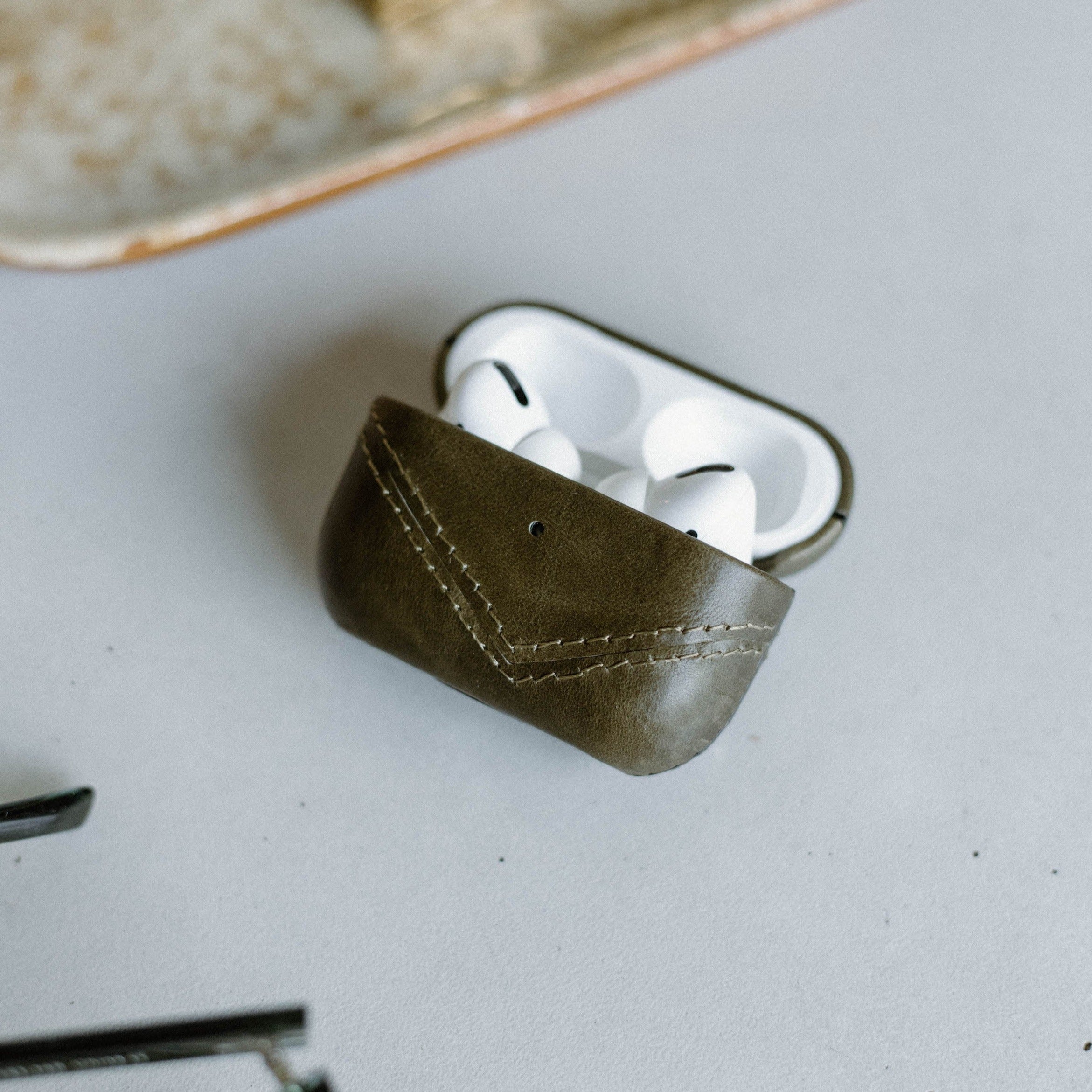 Olive green leather AirPods case with AirPods inside