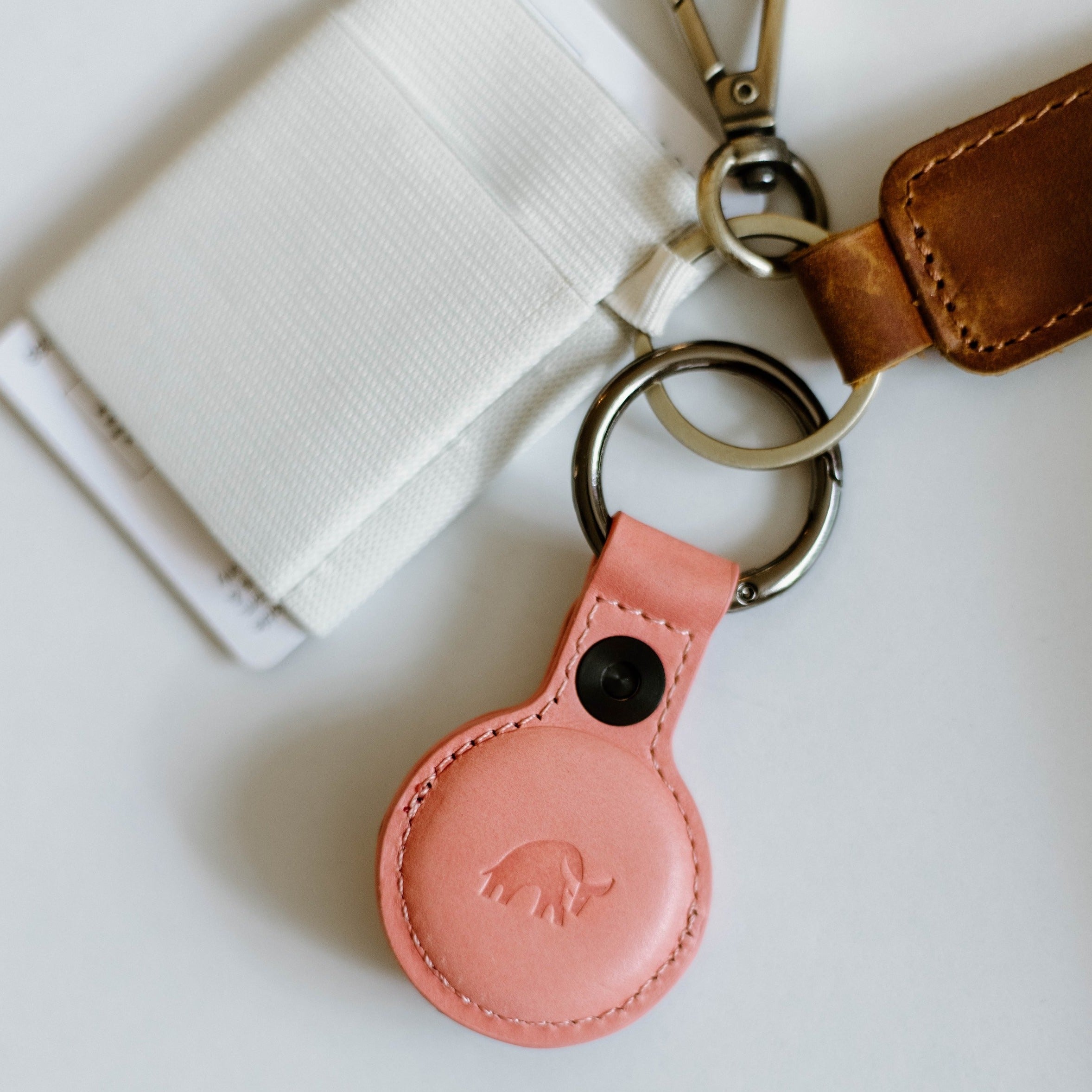 Pink leather keychain holder for AirTag with a bull logo