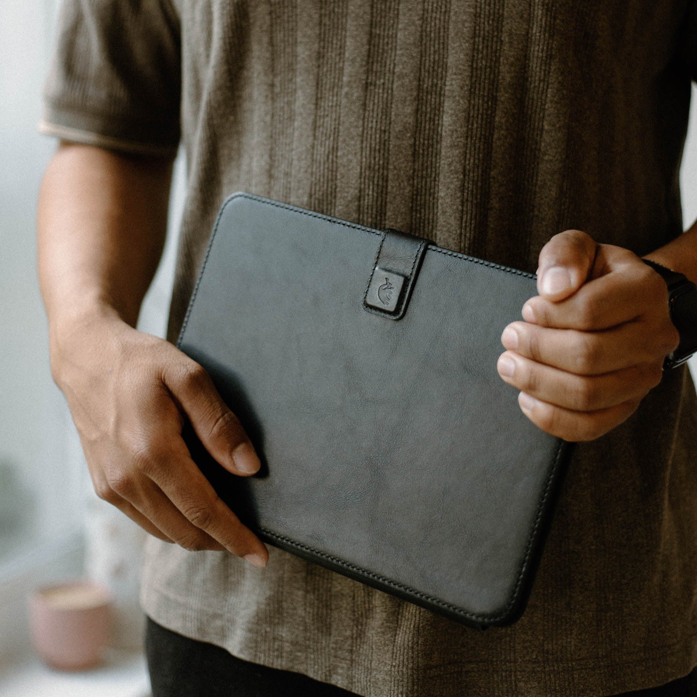 Person holding a black leather iPad case