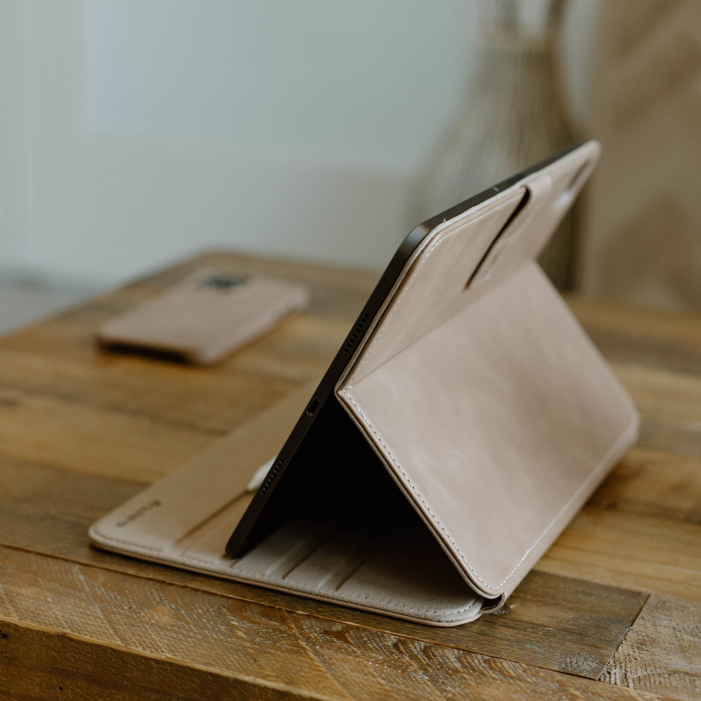 Leather iPad Case in Dune color, displayed with an iPad on a wooden table.