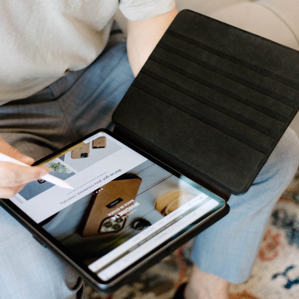 Person using a black leather iPad case with an iPad displaying a website.