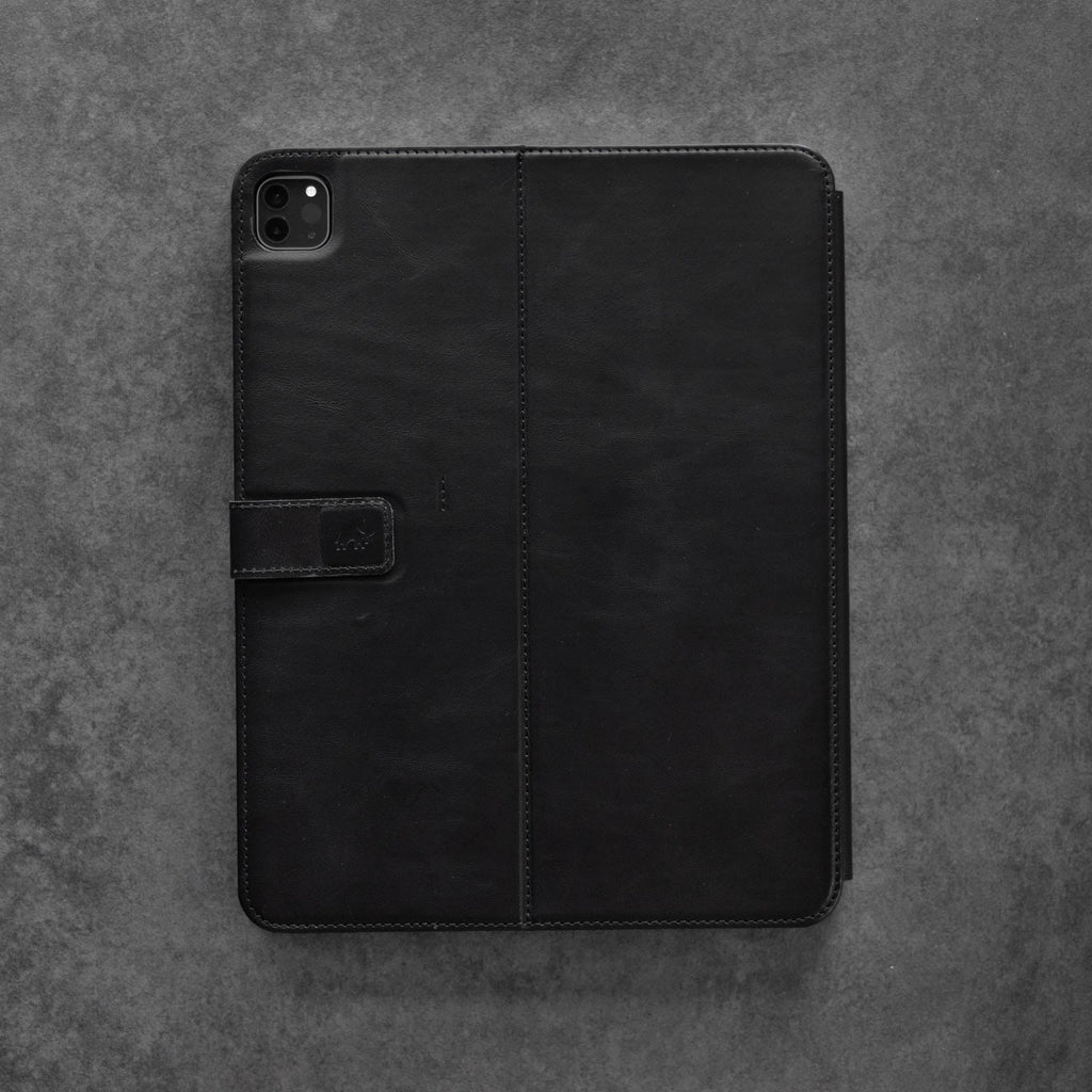 Black leather iPad case with a magnetic closure on a gray background