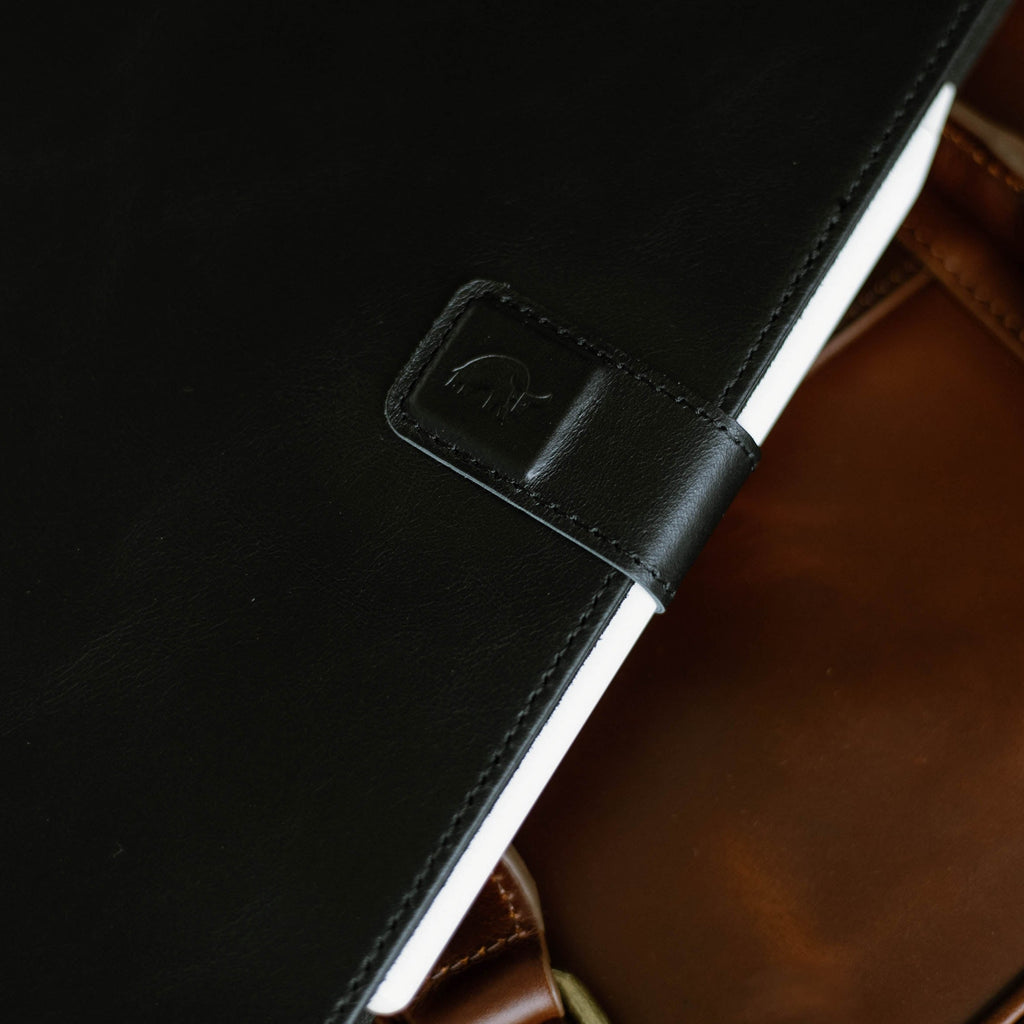 Close-up of a black leather iPad case with a logo, showing texture and design.