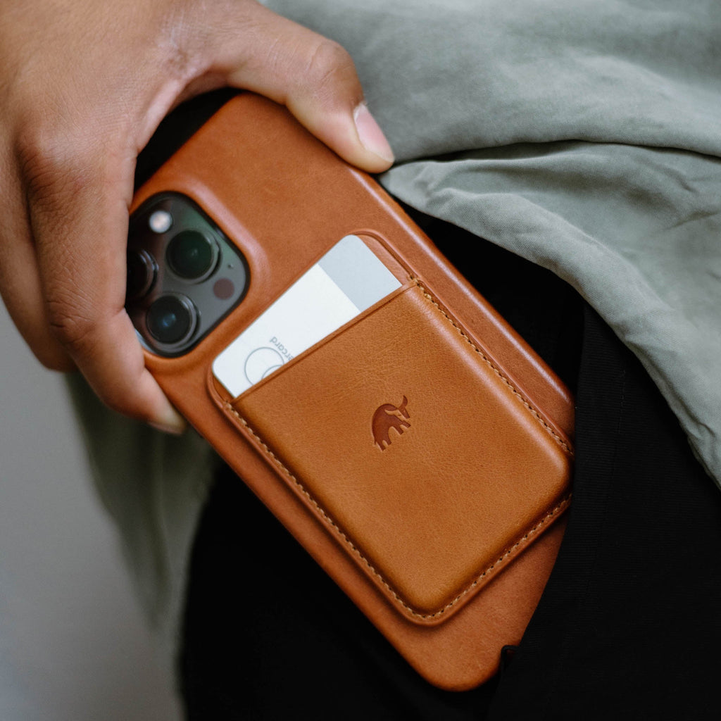 A person holding a phone with a leather magnetic wallet attached, showing the Bullstrap logo.