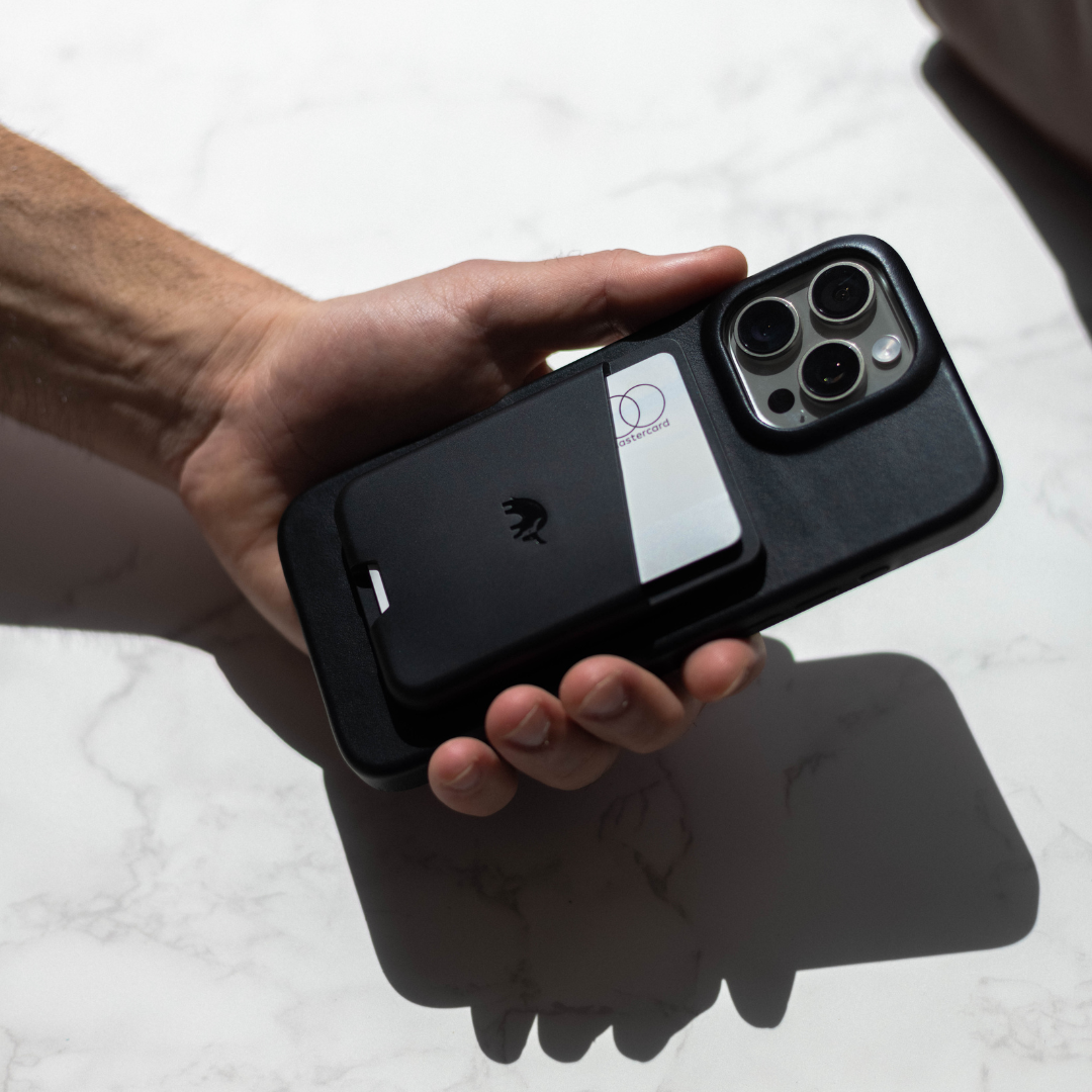 A hand holding a slate leather magnetic wallet with a card visible.
