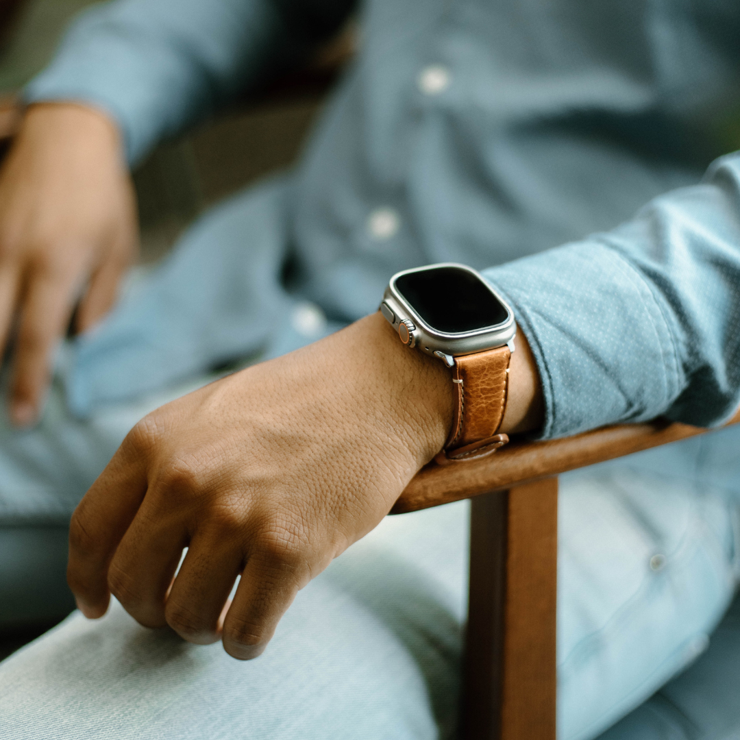 A person wearing a leather Apple Watch strap in a casual setting.