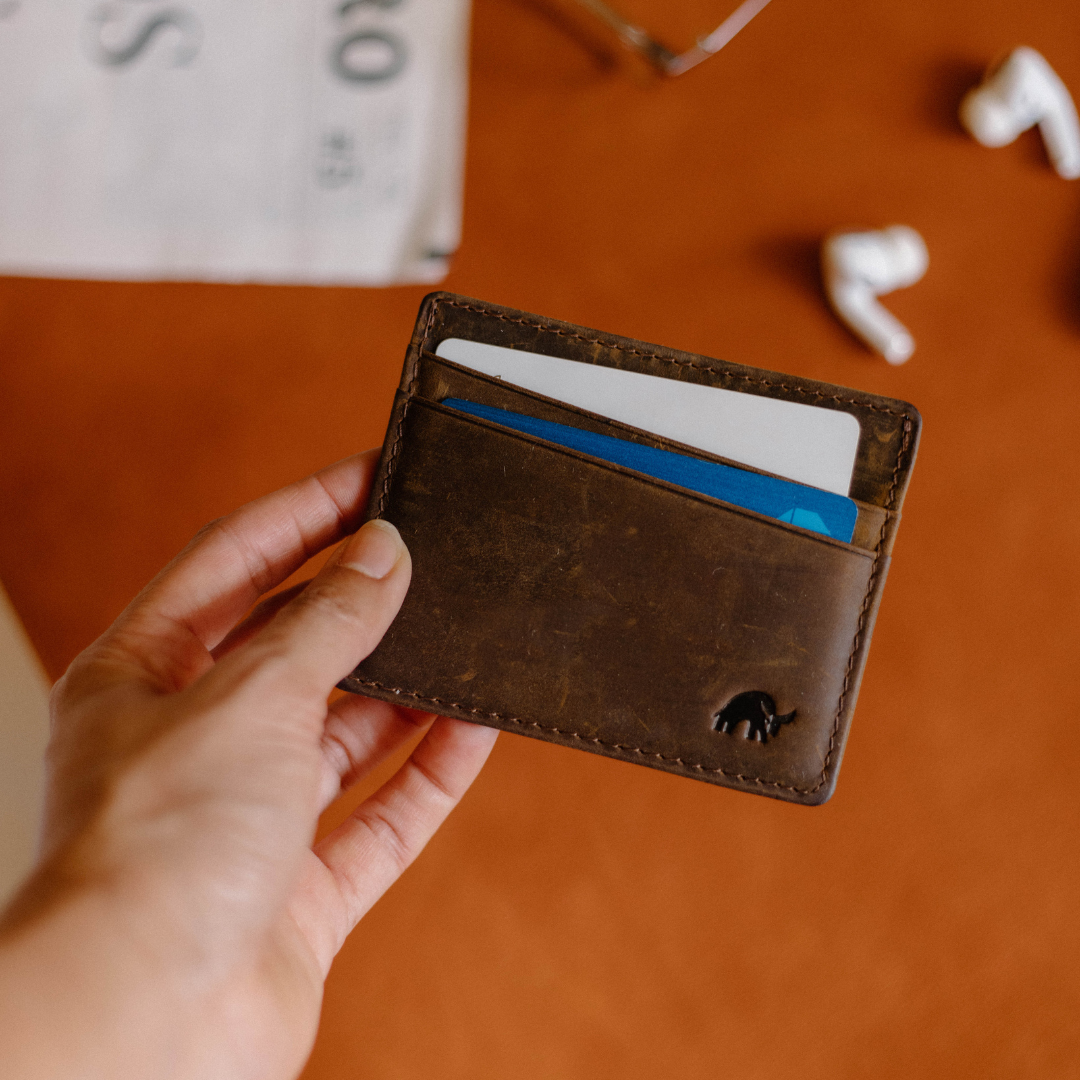 A brown leather card holder with cards visible, featuring a bull logo