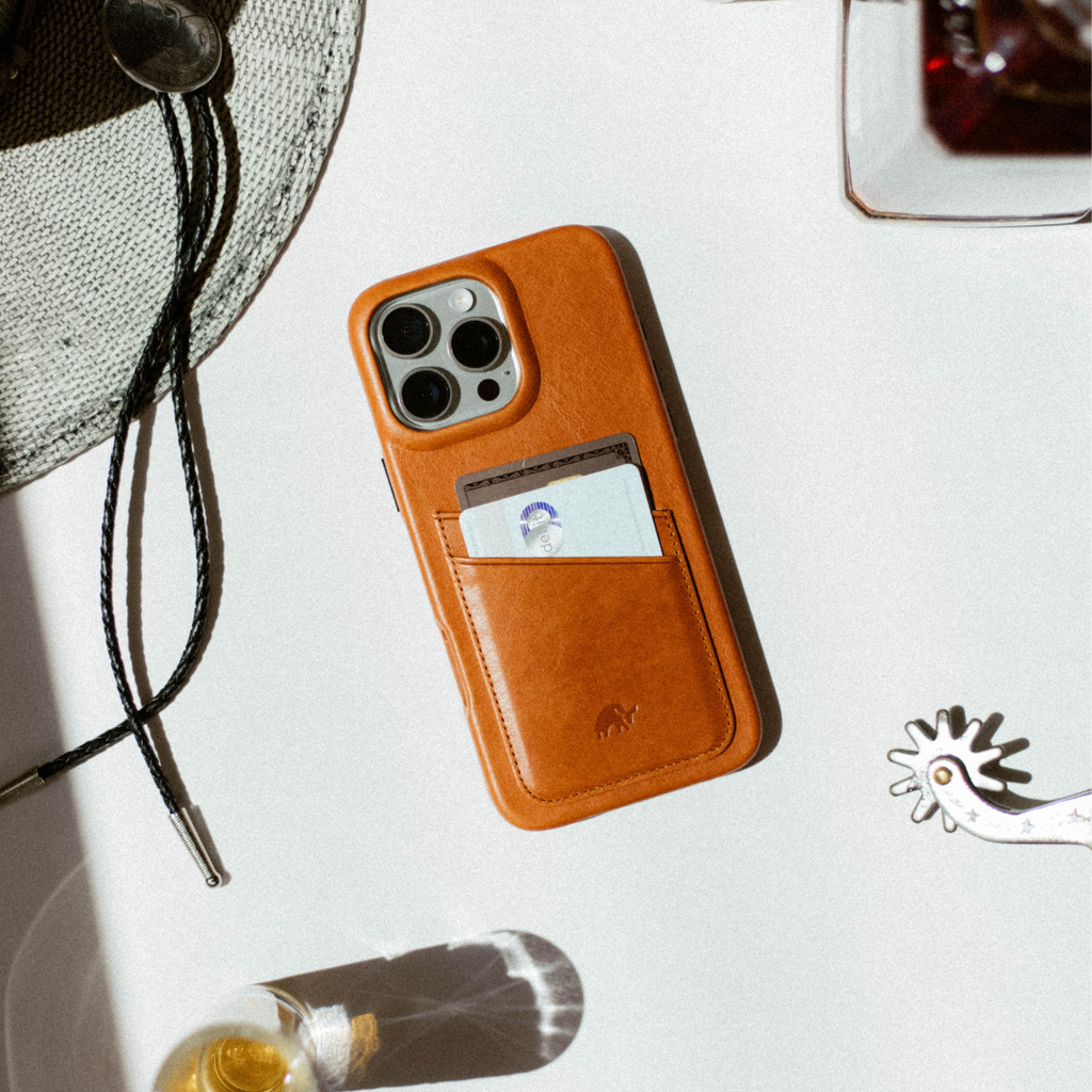 Sienna brown leather iPhone case with stitched rear card pocket holding two cards, flat on white surface