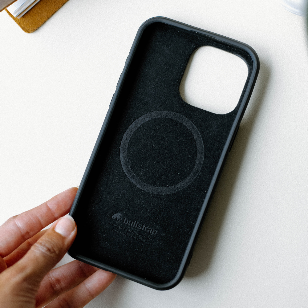 Hand holding the Flex Case - BLACK EDITION with a circular MagSafe area visible