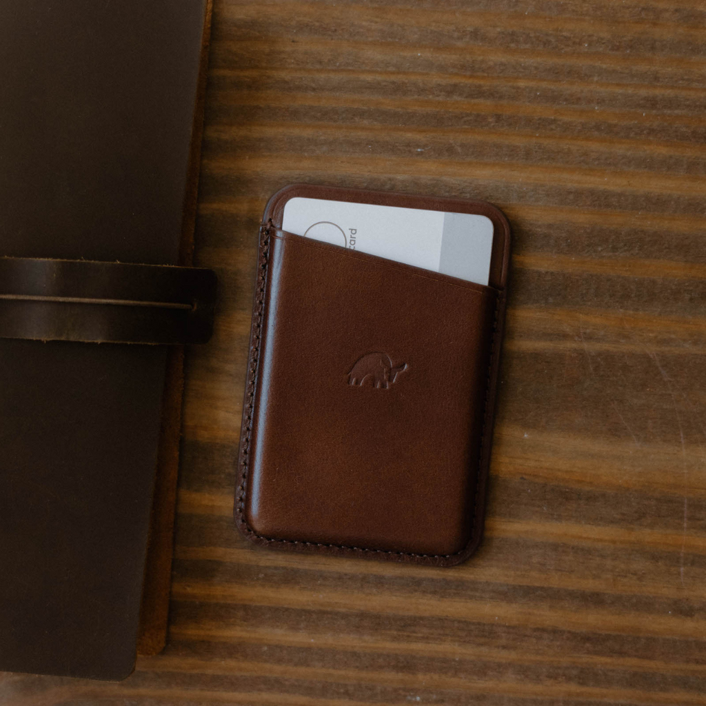 brown leather magnetic card wallet with embossed elephant logo and a partially visible white card