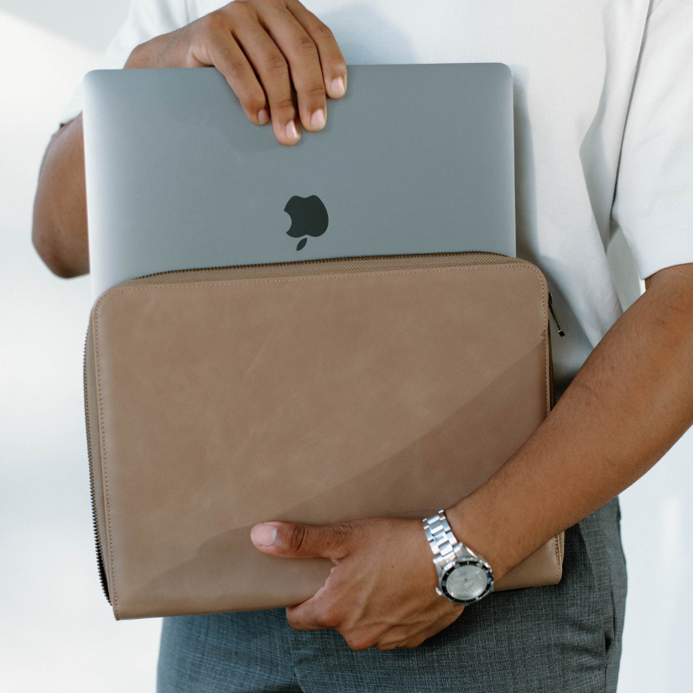 Person holding a DUNE Leather MacBook Sleeve with a MacBook inside