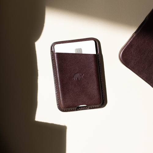 Brown leather card wallet holding a white chip card, top-down view with strong shadow