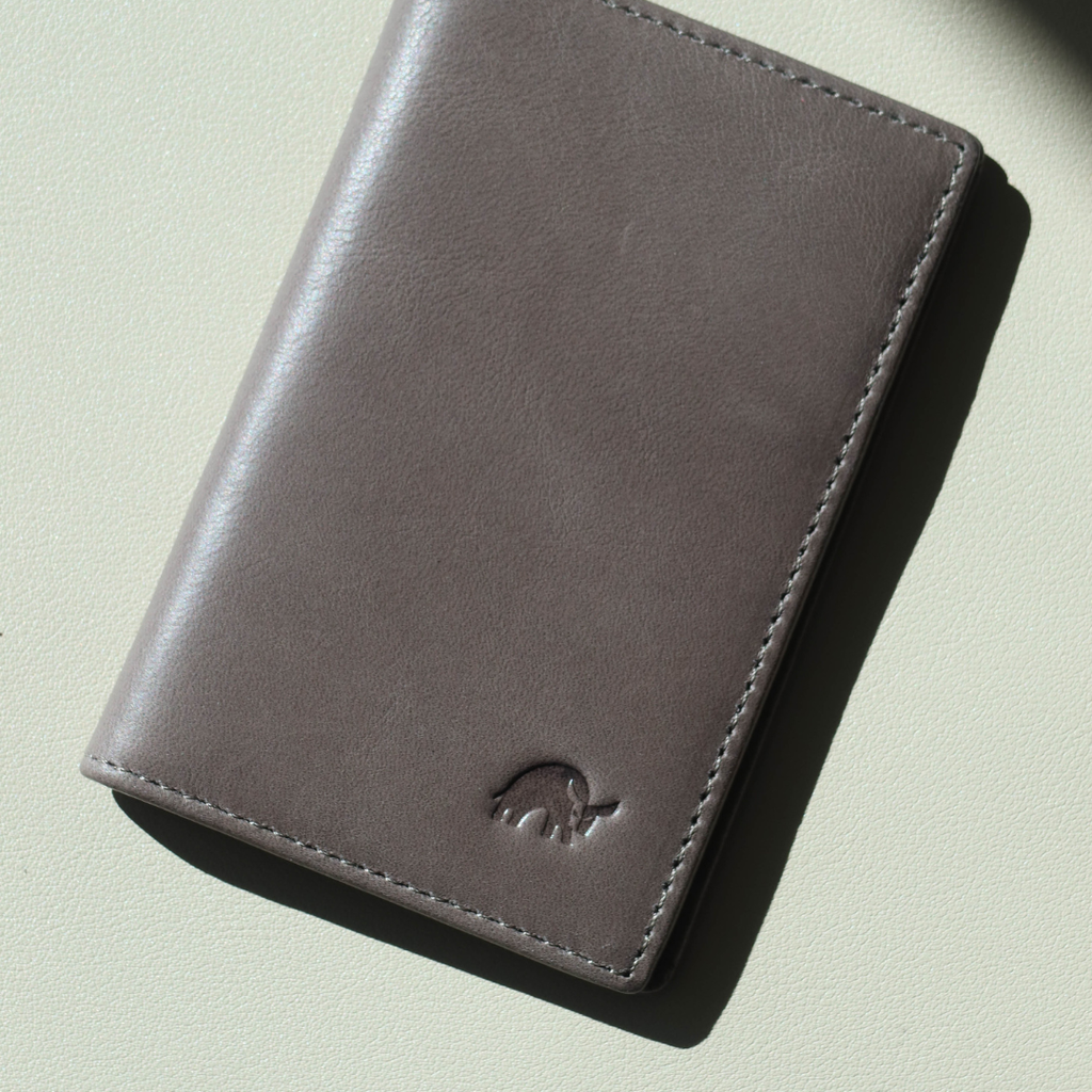 Top-down view of Leather Nav messenger wallet in slate showing smooth leather, stitched edges and embossed rhino logo on a light textured background