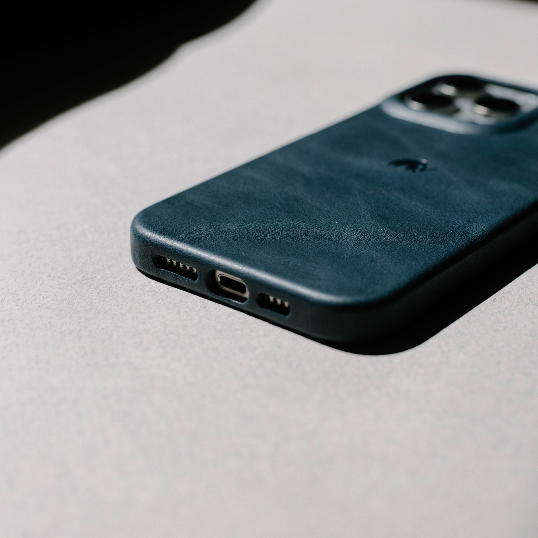 Ocean-blue leather smartphone case lying face down, showing charging port and dual-camera cutout.