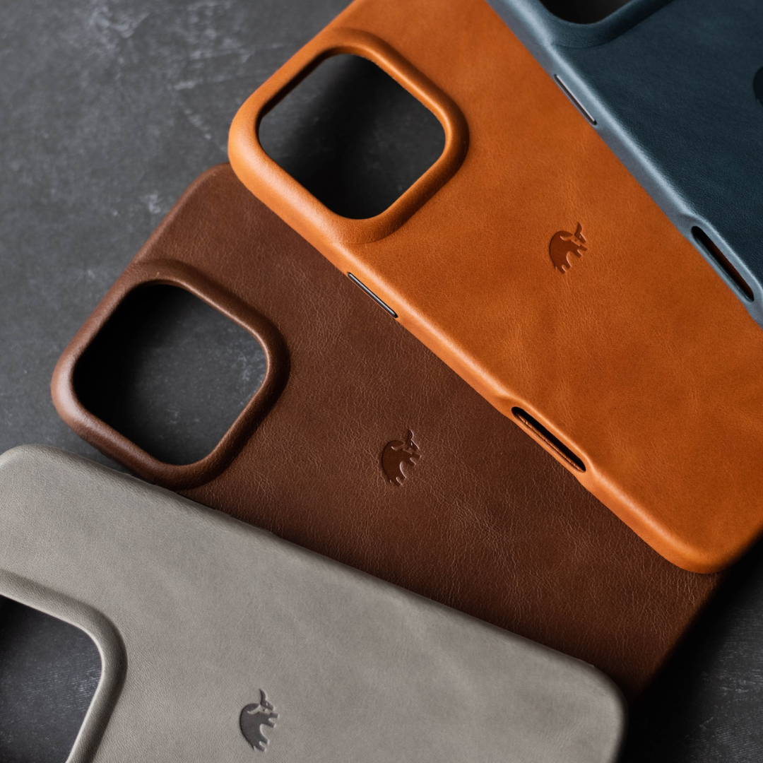Four leather phone cases in various colors: brown, orange, blue, and gray, with a logo on each case.