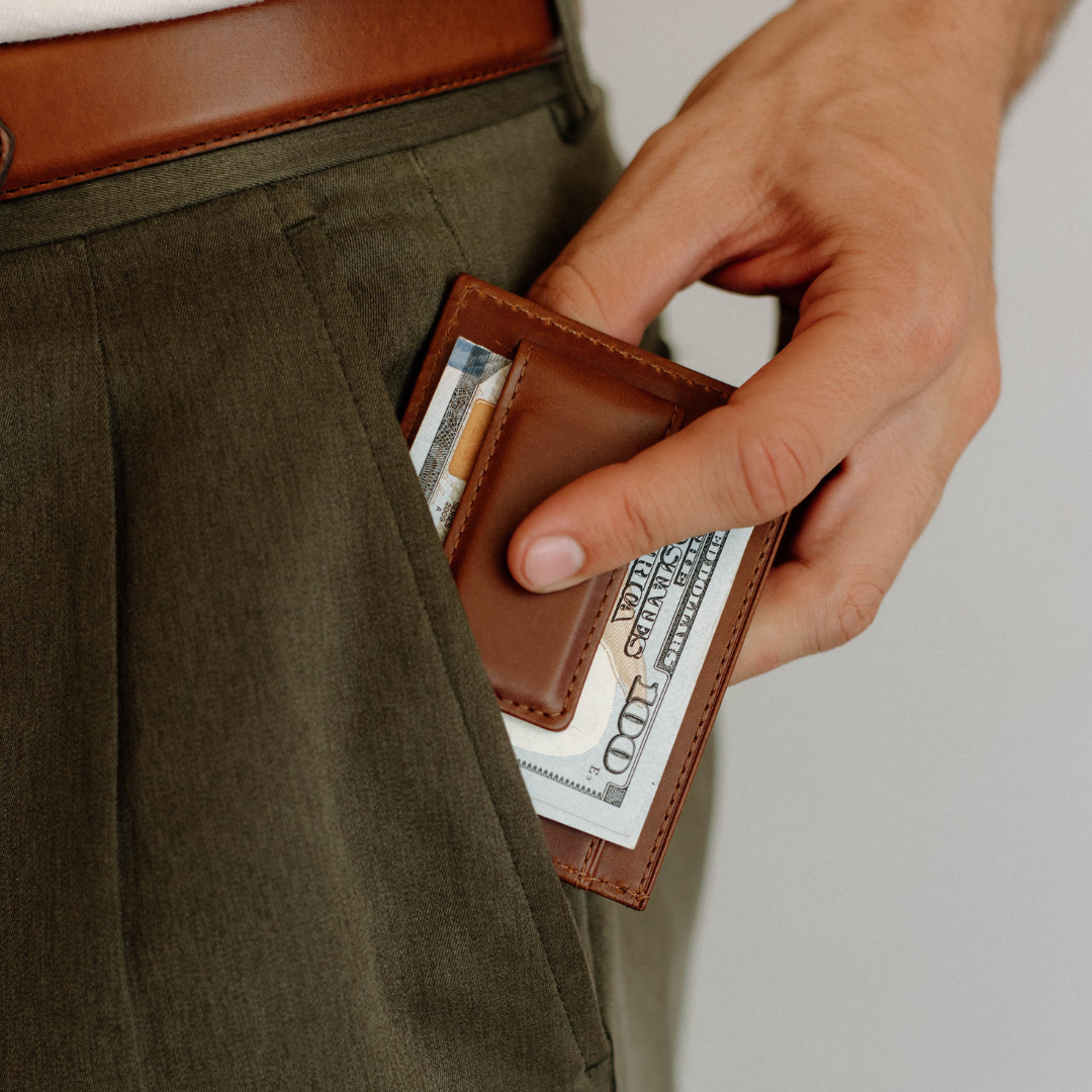 A hand holding a wallet with cash, showcasing the Bullstrap Reserve.