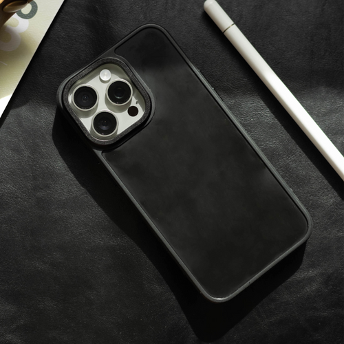 Black smartphone in a black case showing triple-lens camera, next to a white stylus on a dark leather surface.
