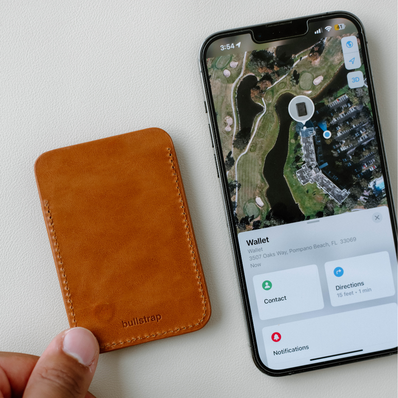 Leather card wallet stamped 'bullstrap' beside an iPhone showing a map with a 'Wallet' panel and navigation options.