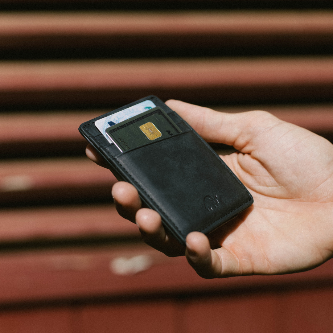 Black slim card wallet held in a hand, two cards visible—one with an EMV chip