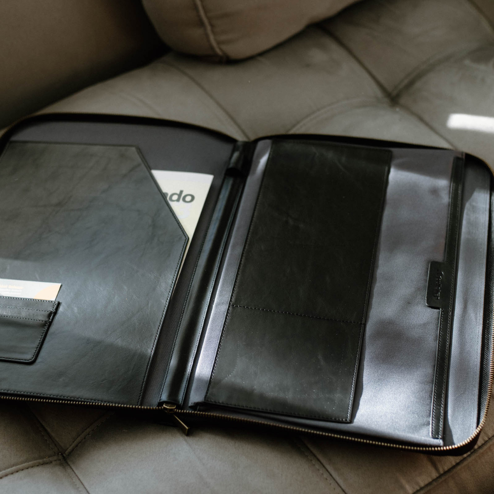 Interior view of a black leather MacBook sleeve showing pockets and compartments.