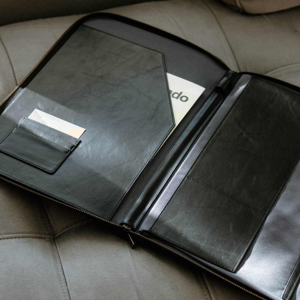 Interior view of a black leather MacBook sleeve showing pockets and compartments.